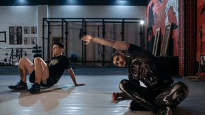 Two men stretching on the gym floor, preparing for a workout session.